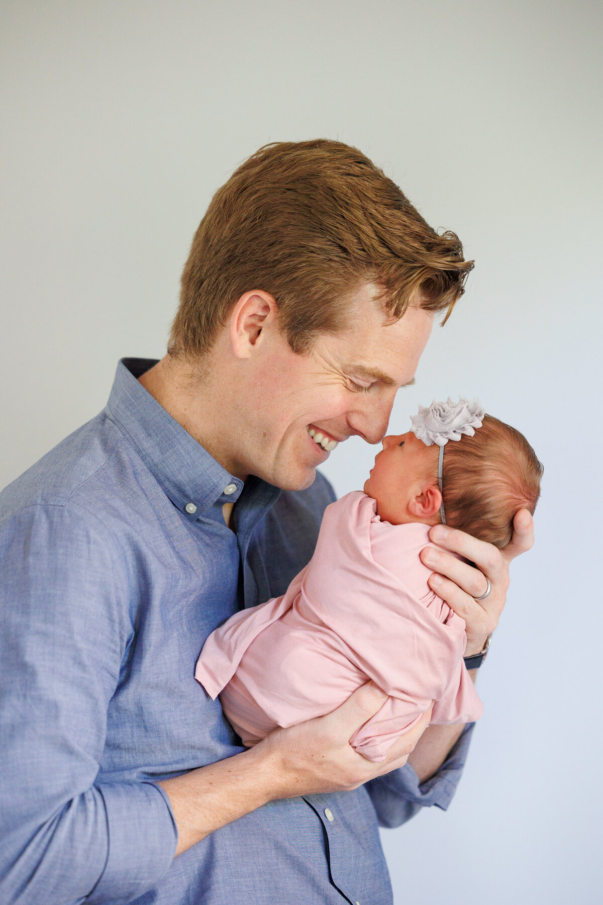 Father holding a newborn baby girl wearing pink