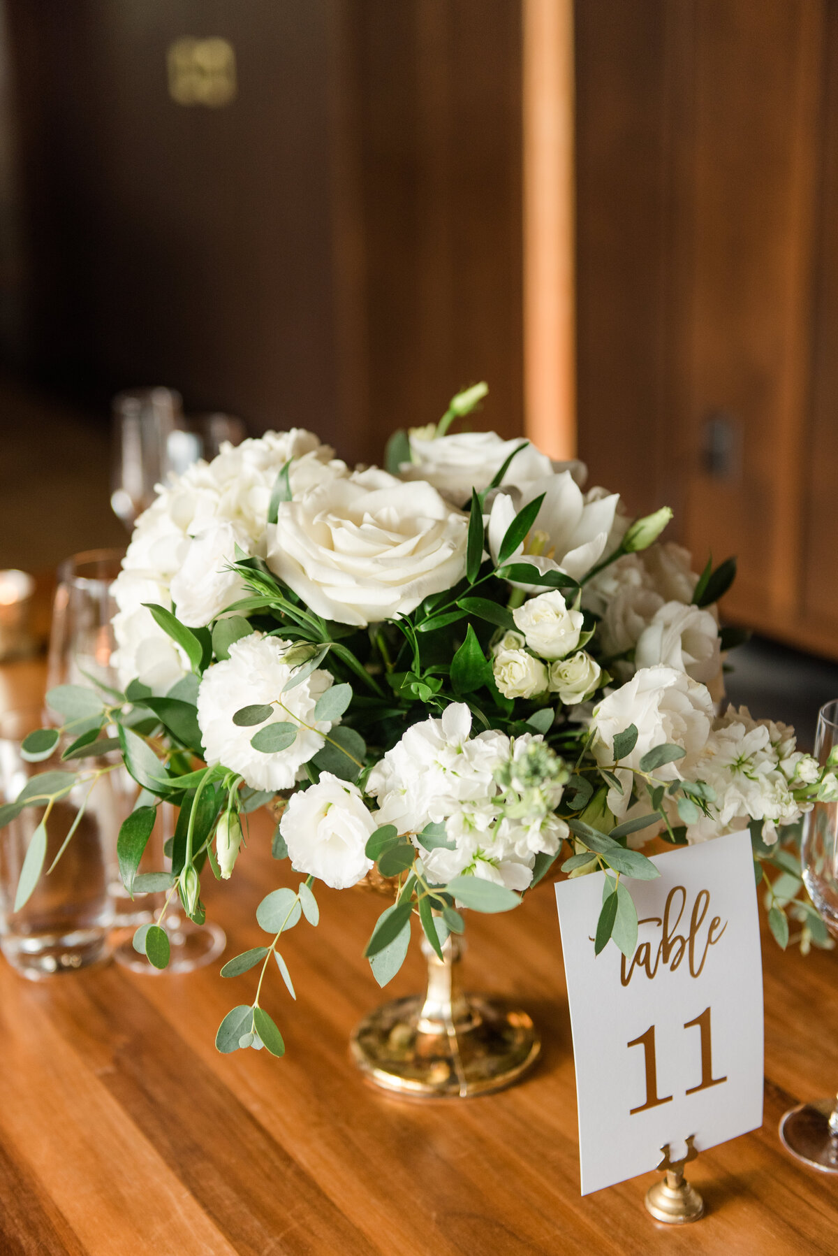 White floral arrangement for a  wedding reception table in a gold mercury glass compote