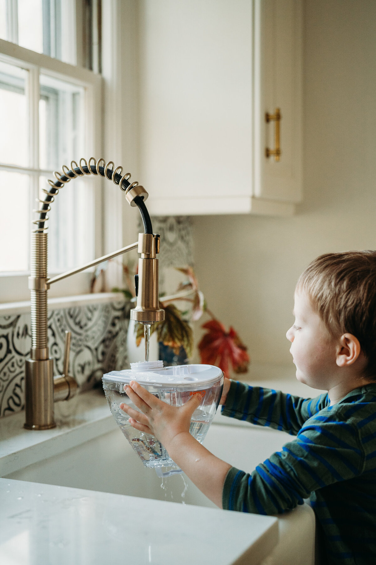 boy fills humidifier in kitchen sink
