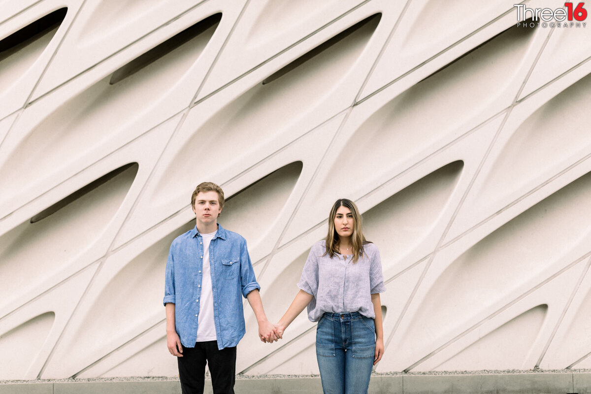 Engaged couple hold hands a look at the camera