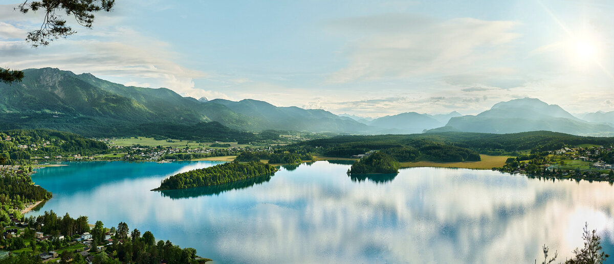 Weitblick über den Faaker See im warmen Licht der Abendsonne – frühlingshafte Landschaftsaufnahme mit klarer Sicht auf Berge, Wasser und Wiesen