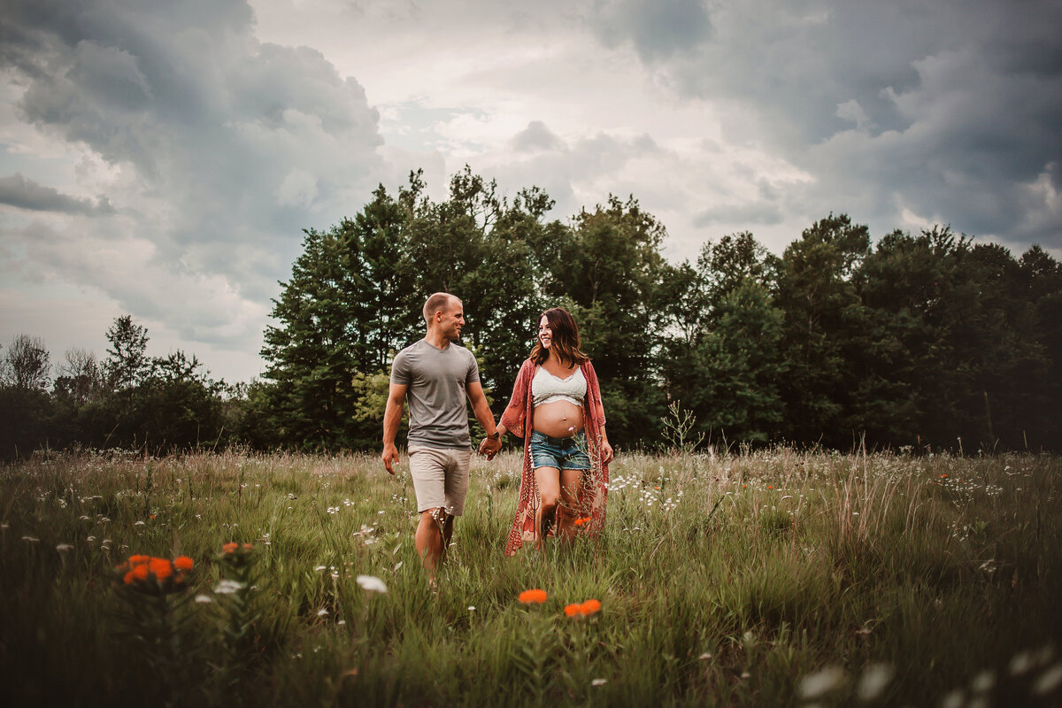 Expecting couple walking in a flower field