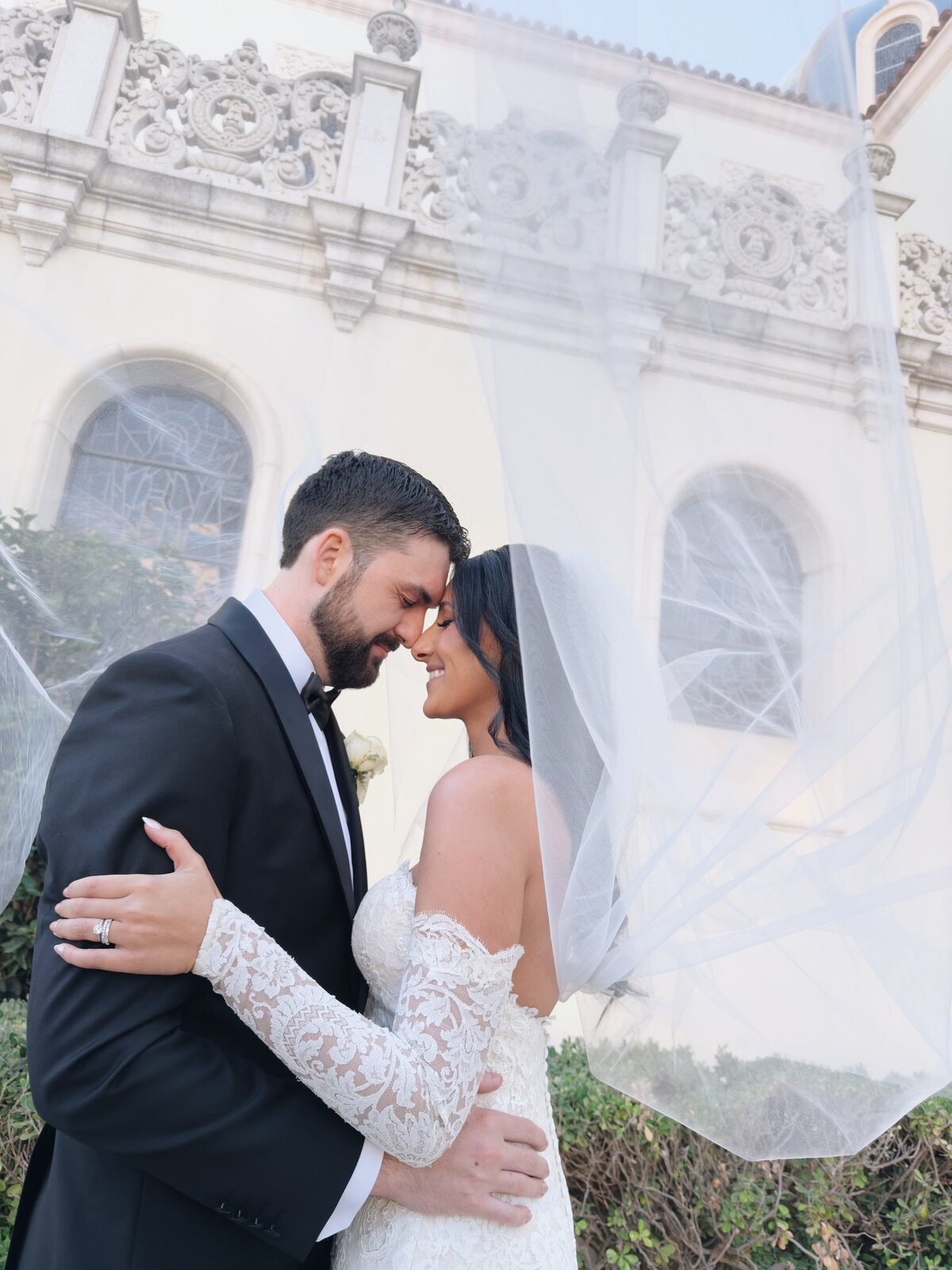 Bride and groom kissing under the veil outside of The Immaculata Catholic Church on the University of San Diego's campus.