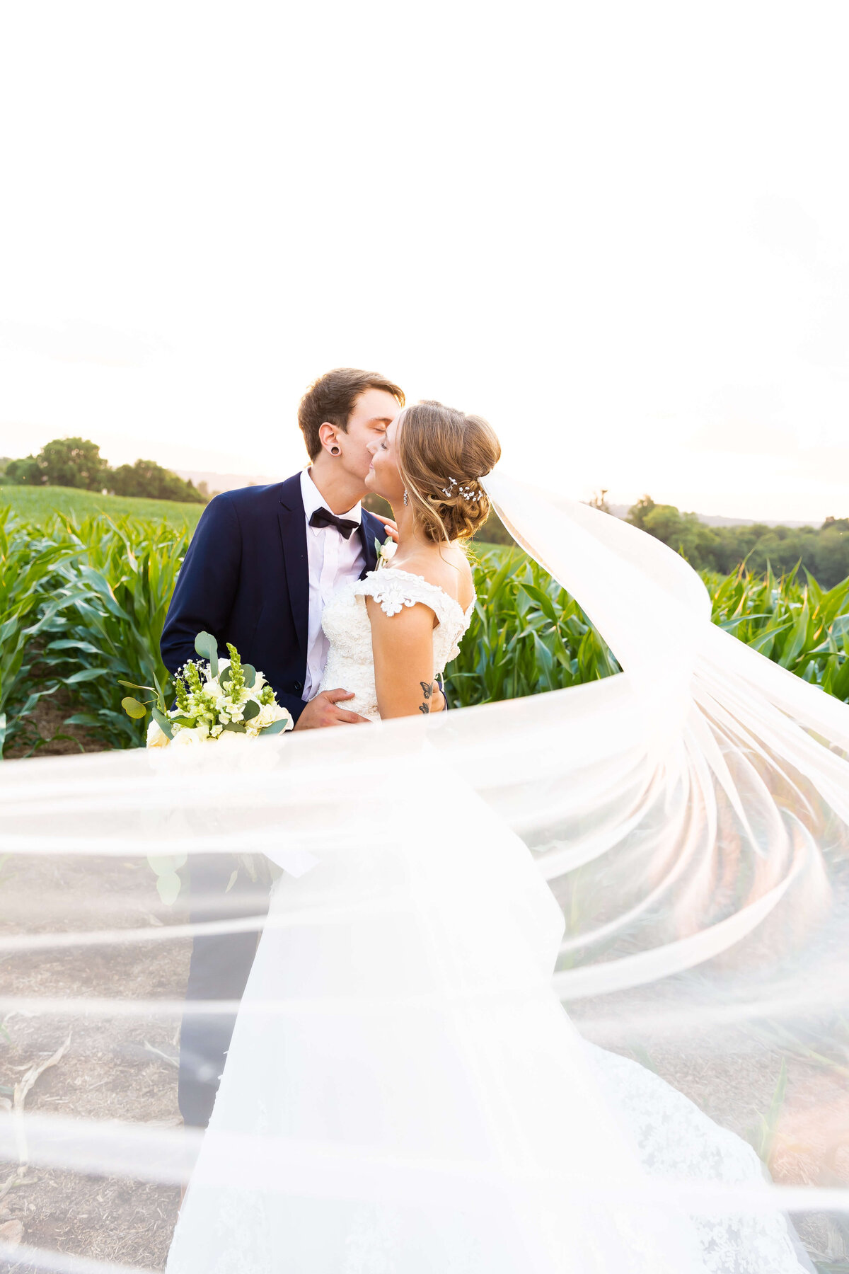 Bride and groom kissing with brides veil trailing around them