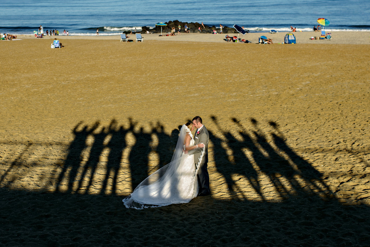 A bride and groom are surrounded by the shadows of their wedding party at this long branch new jersey wedding.