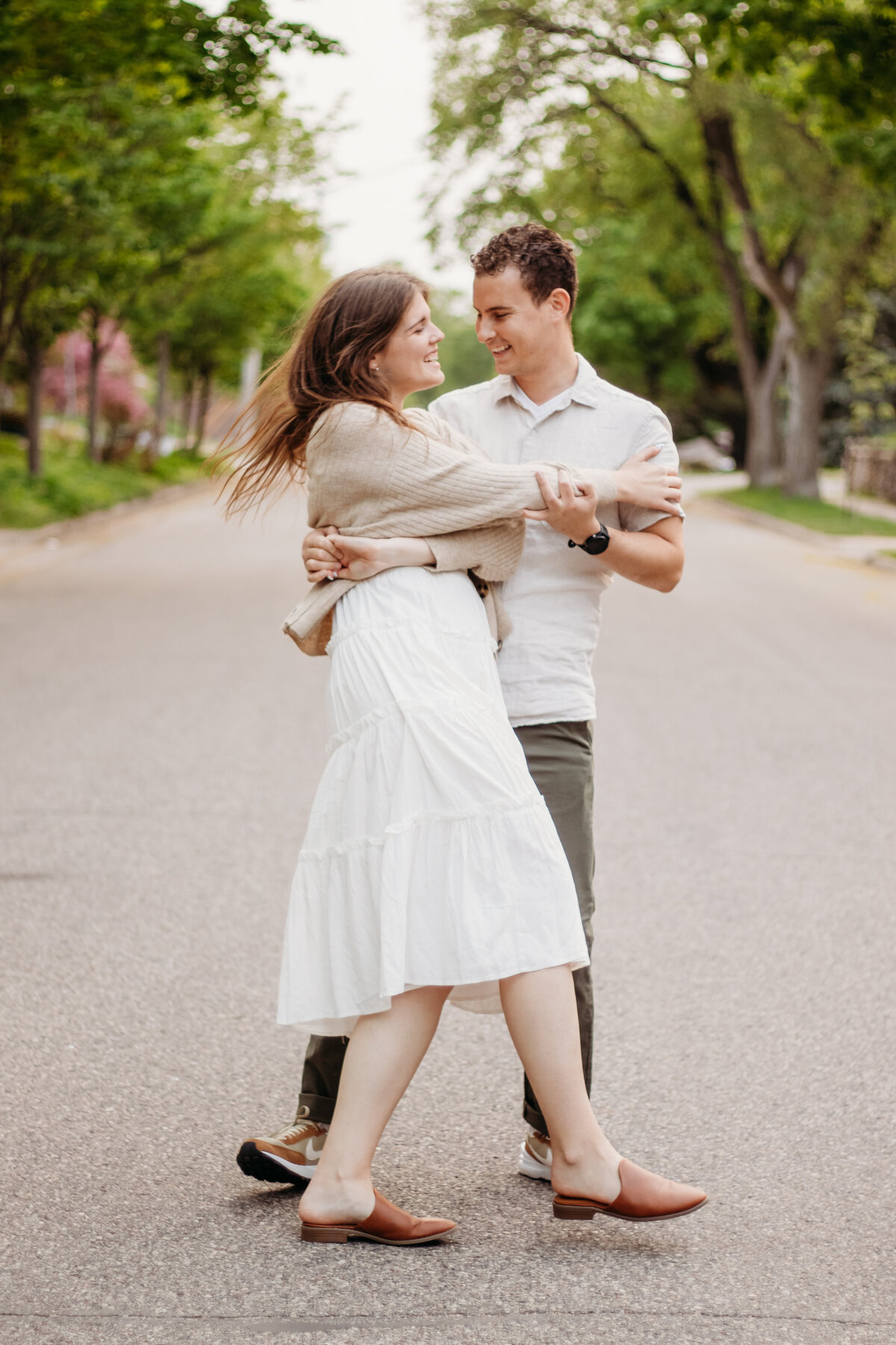 A happy couple dances in the streets during a sweet session with a Duluth wedding photographer, S Jacobson Photography.