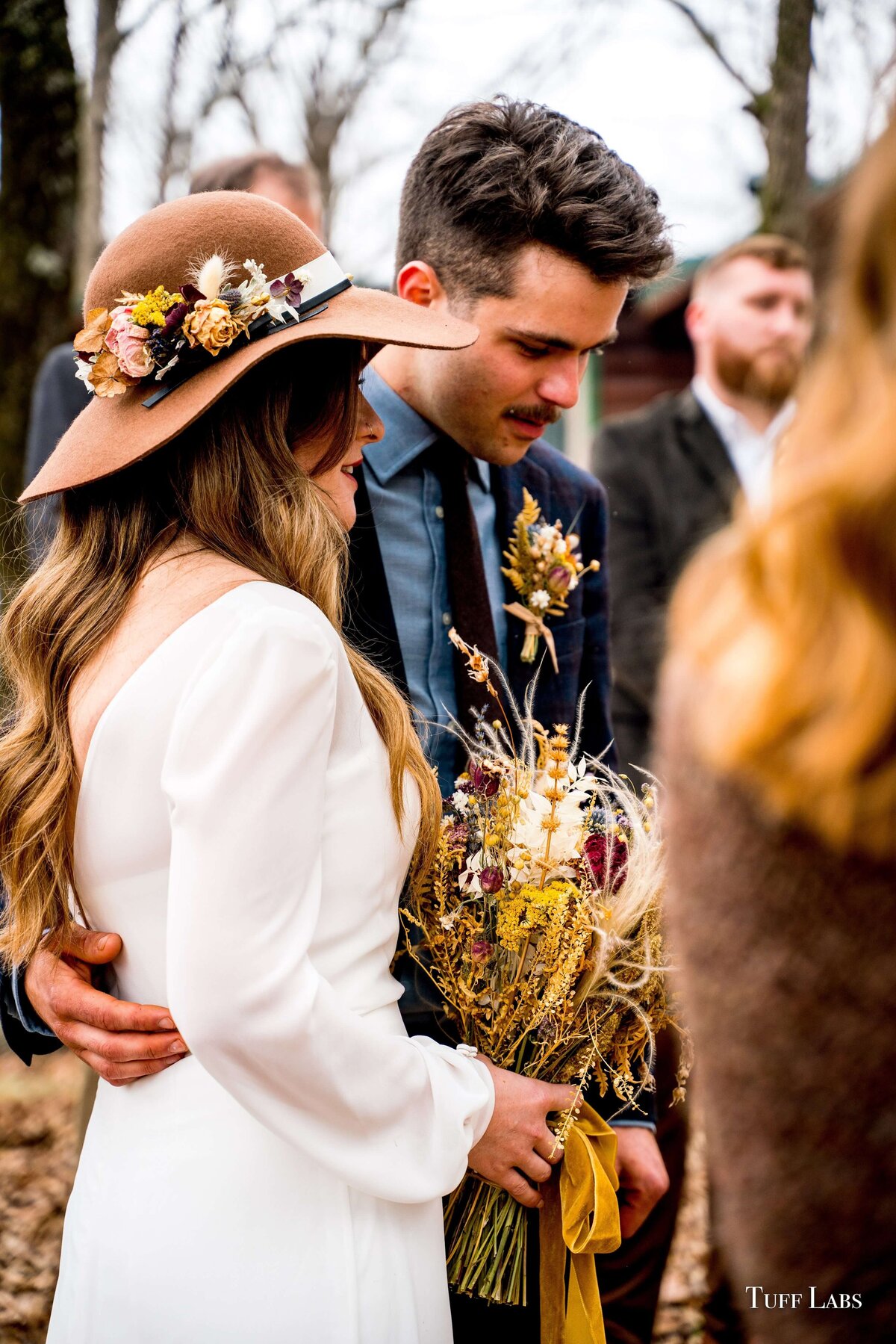 Bride and groom during their outdoor wedding ceremony as she holds her dried floral bouquet.