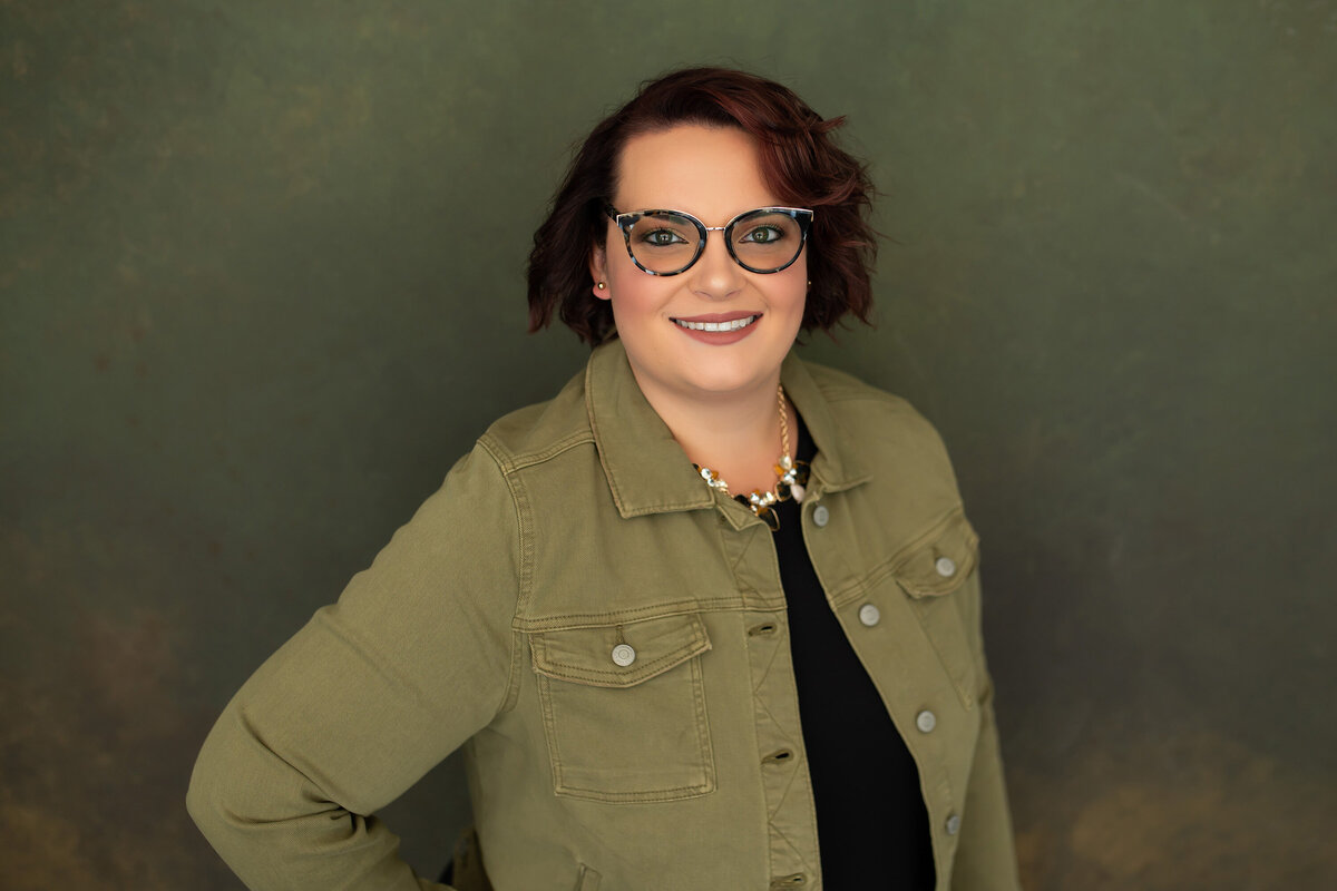 A saleswoman from Sussex, WI poses from her professional headshots with an olive green theme.