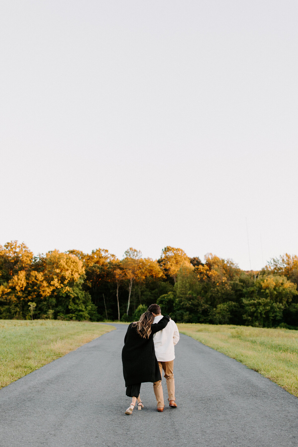couple with their arms around each other walking down a road