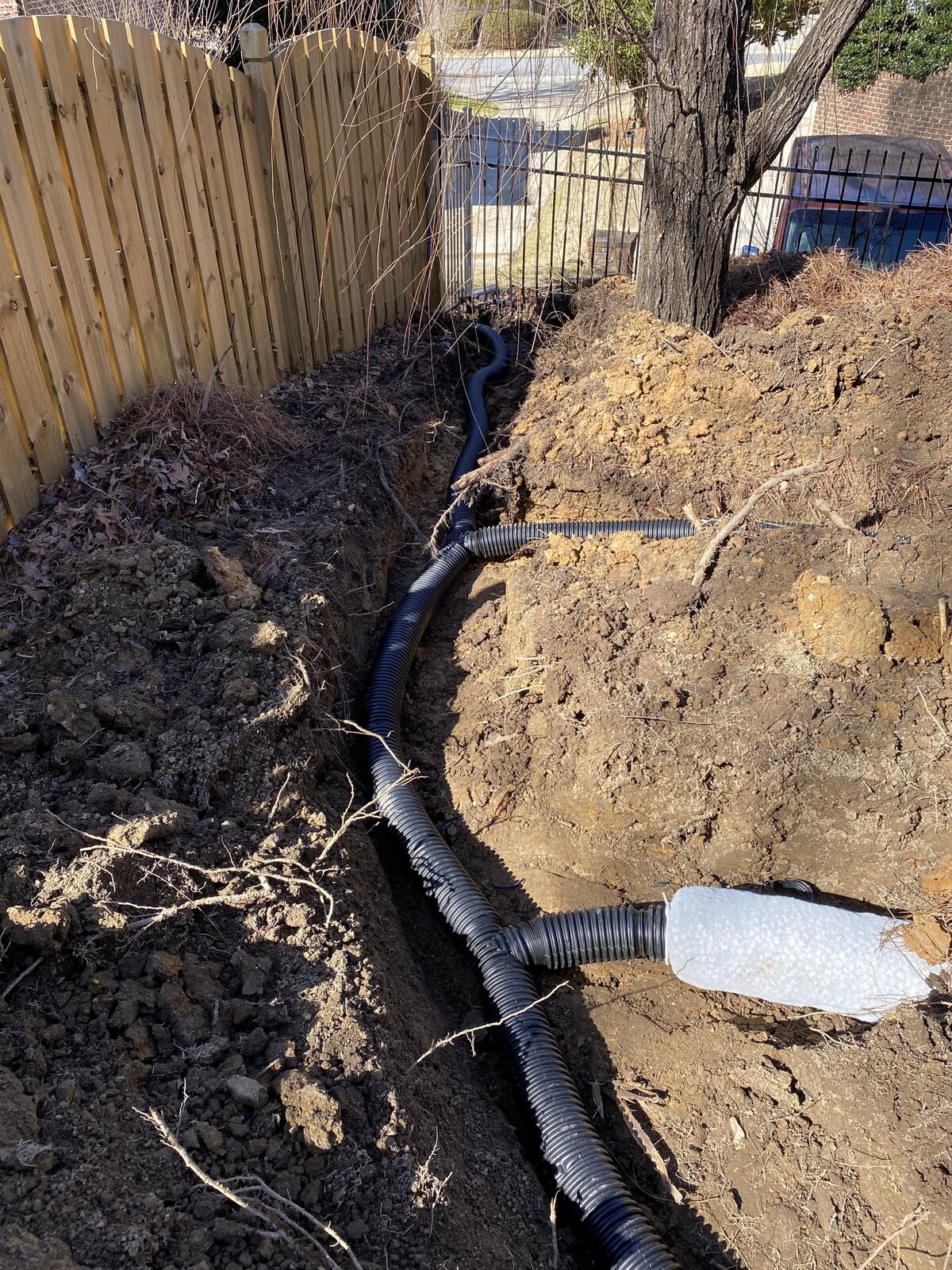 drainage-hoses-in-dirt-trench-next-to-wodden-fence