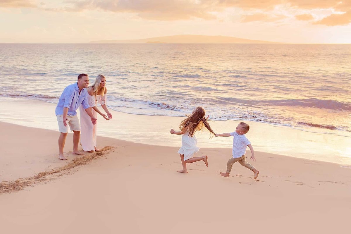 Fun family racing in the sand, little boy yanks sister's hair at the finish line during their family session at sunset
