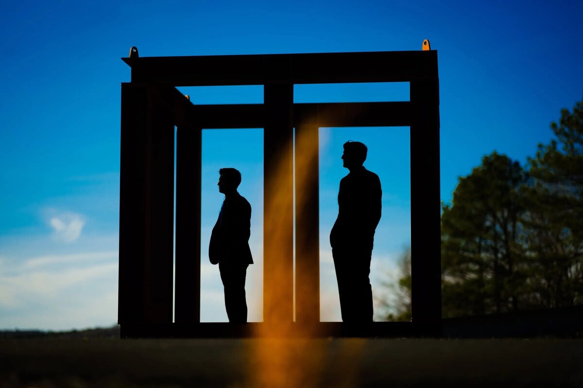 Two men standing in a framed box looking out