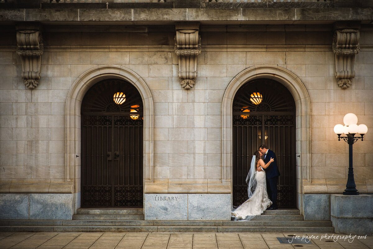 A bride and groom kissing in an archway.