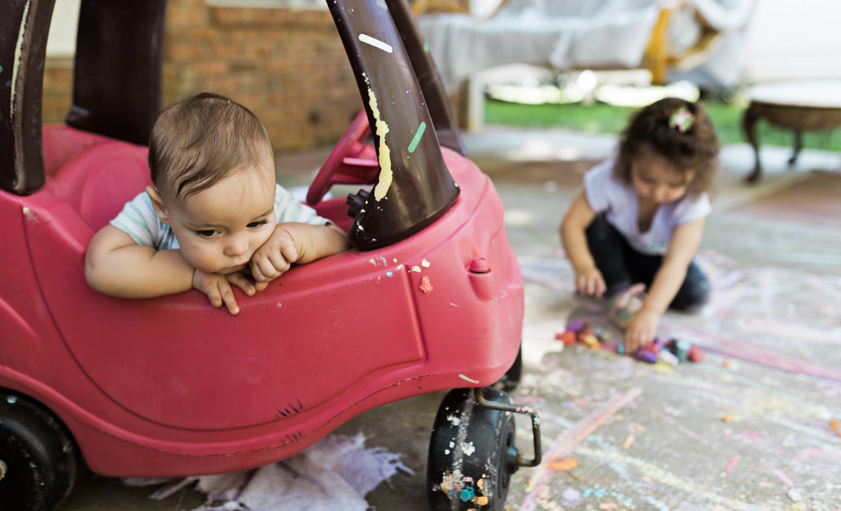 charlotte documentary photographer captures a day in the life of chilfren playing with cozy coupe and chalk