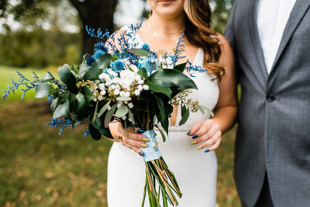 Bright blue wedding floral bouquet for a midnight themed wedding with bride holding the bouquet as she walks with her groom captured by Virginia wedding photographer