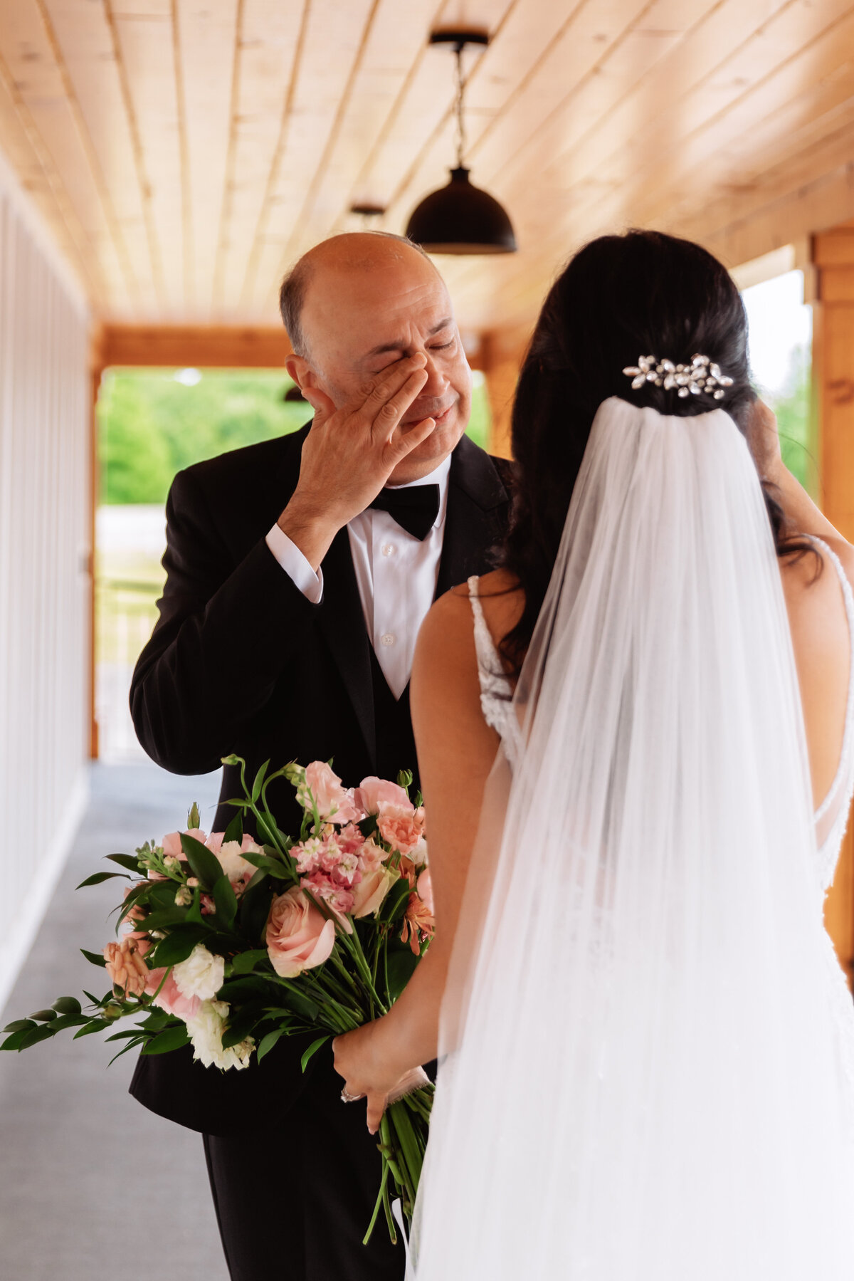 Shannon Lee, from Love Like Wild Photography, captures an emotional father wiping a tear as he sees his daughter, the bride, holding her bouquet.