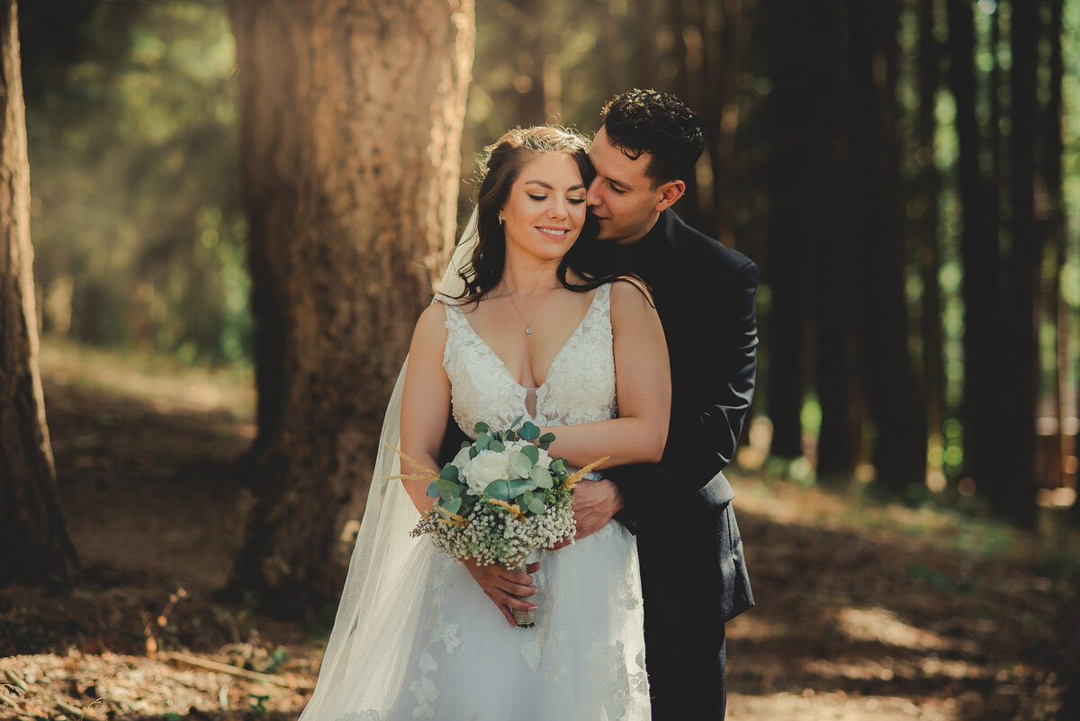 groom kissing bride in forest
