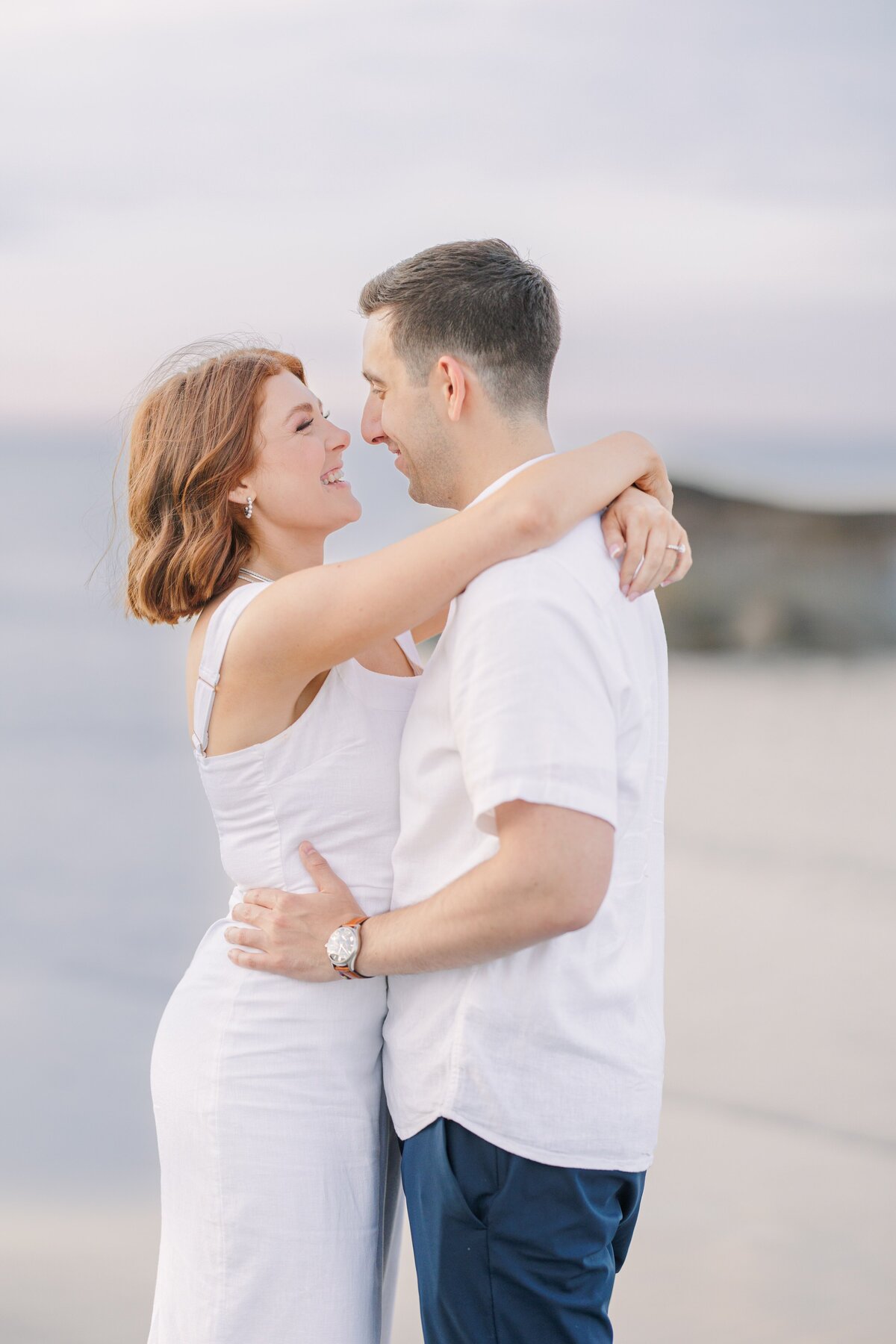 A couple hugging and snuggling at sunset on Wingaersheek Beach during their engagement portraits.