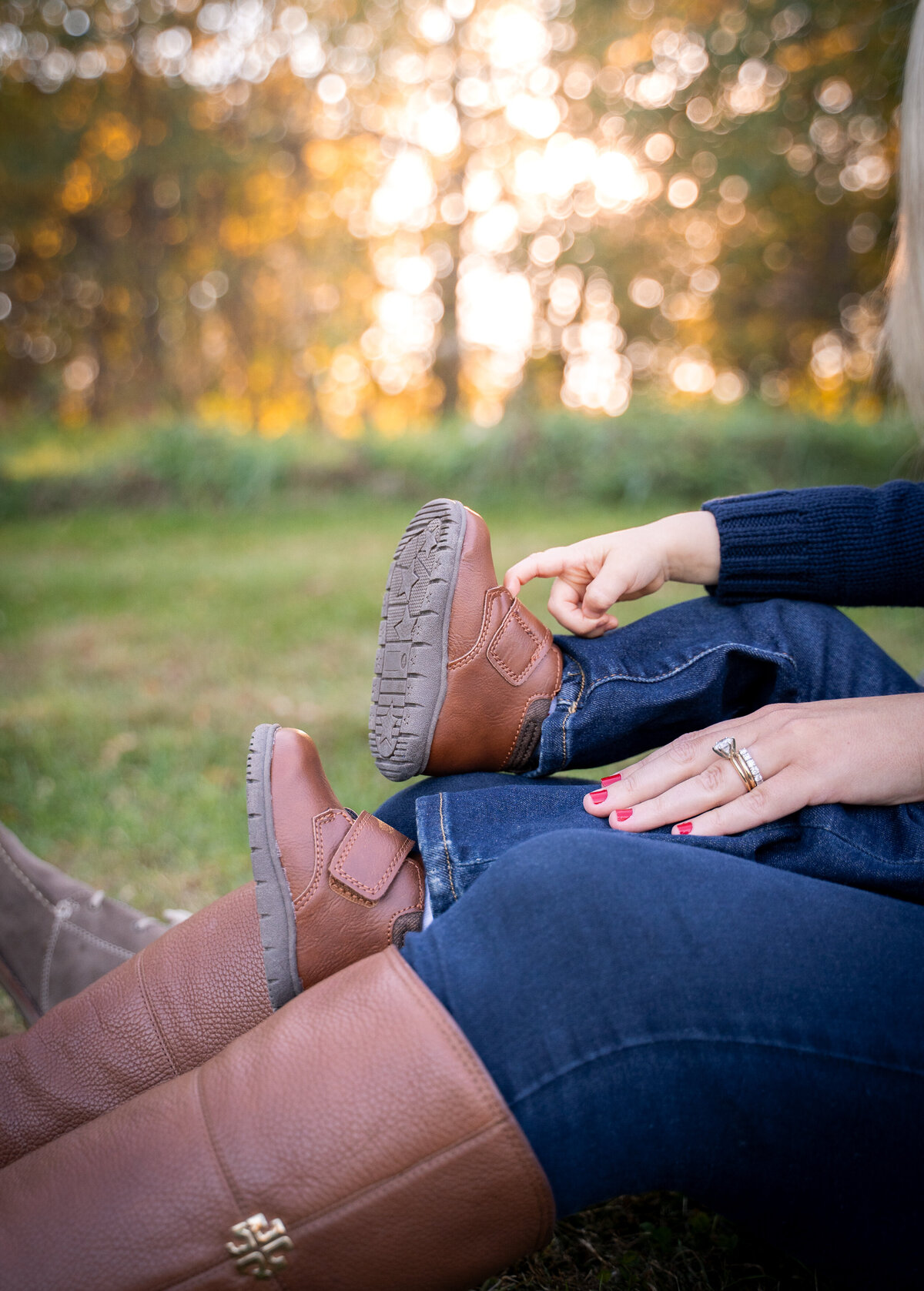 Baby hands touching his foot while sitting on moms lap