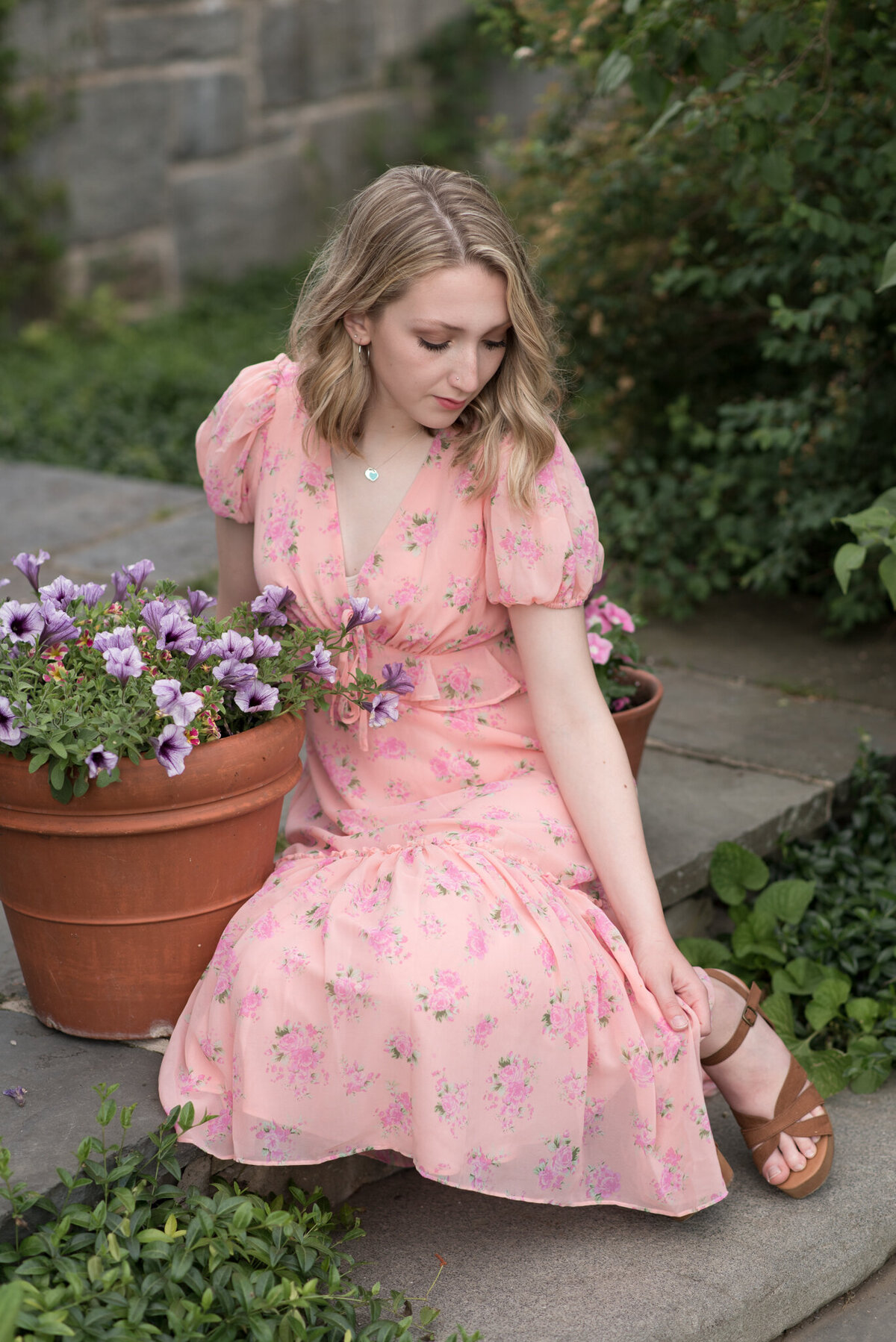 Girl in pink dress, looking down at her feet in garden