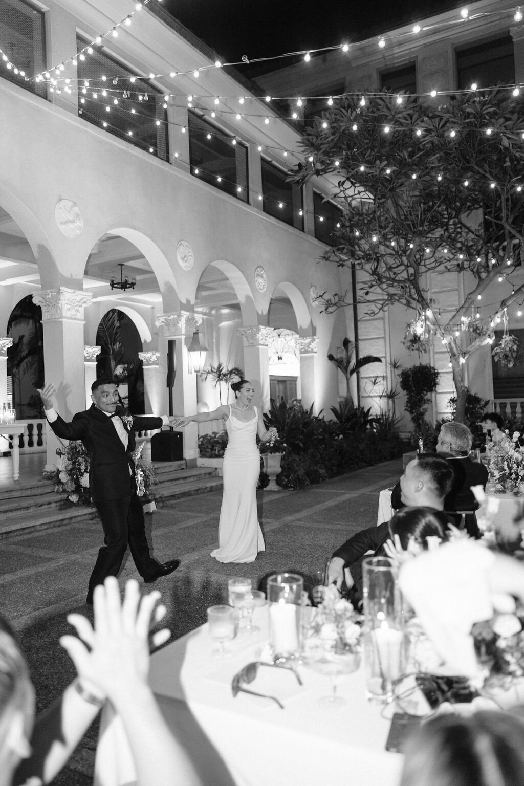 Bride and groom first dance, groom is puttin g an arm out cheering while guests are clapping