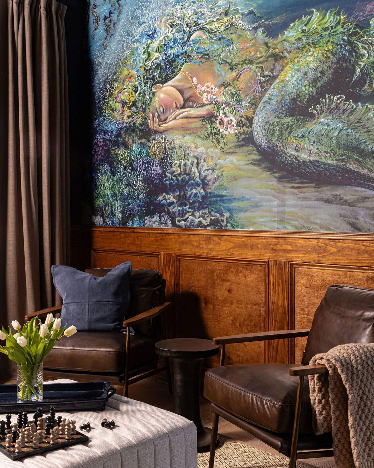 lounge with mural on walls, wood paneling, and leather chairs