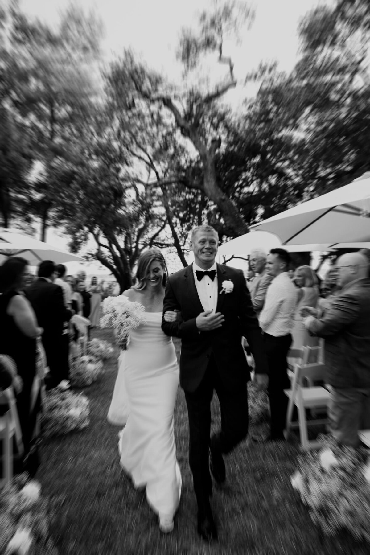 Black and white photo of bride and groom walking down the aisle captured by  Charleston wedding  photographers