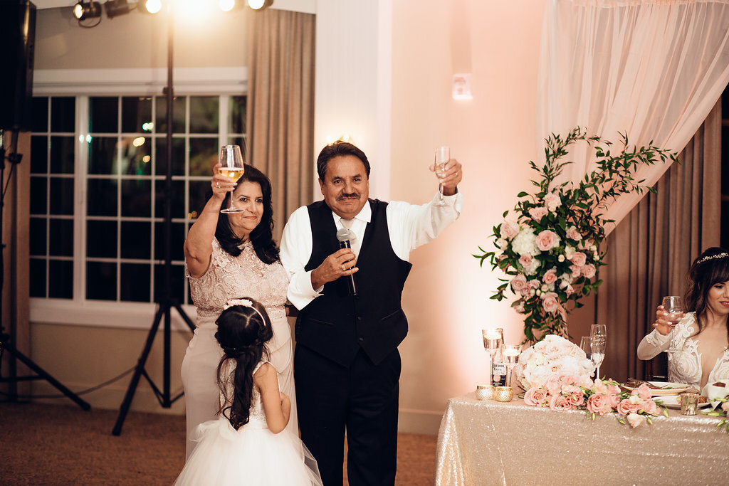 Wedding Photograph Of Man in Black Suit And Woman In Light Brown Dress Raising Their Wine Glasses Los Angeles