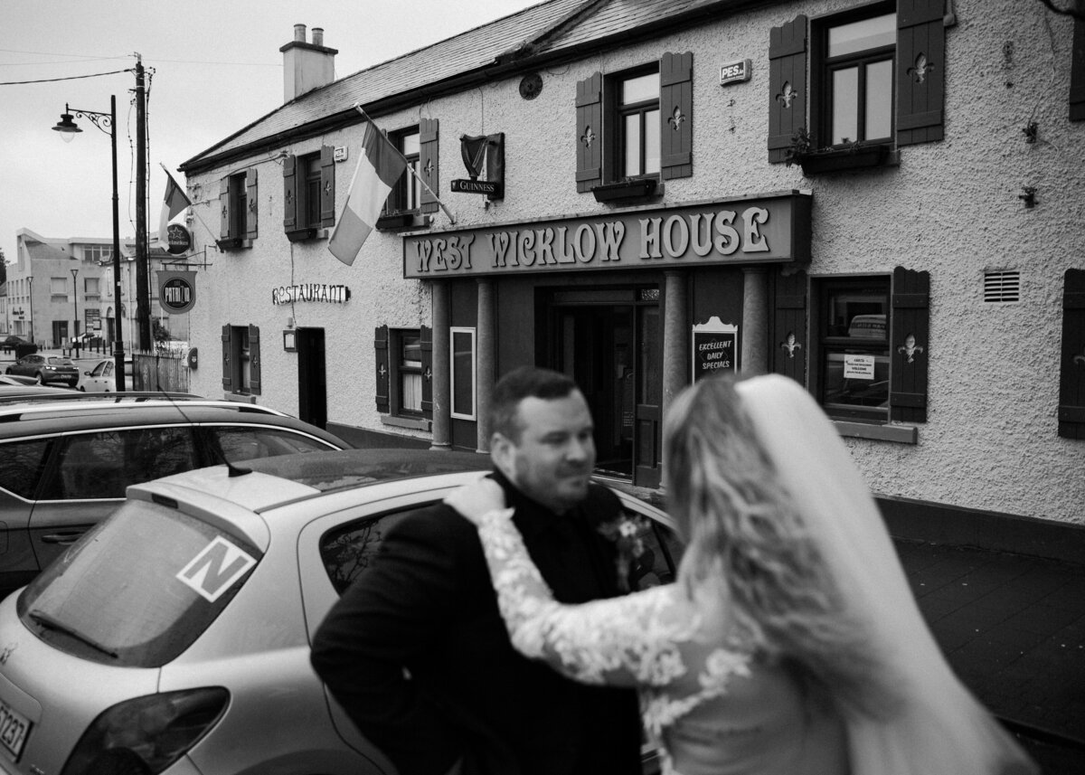 A black and white photo of a couple embracing in front of the West Wicklow House pub