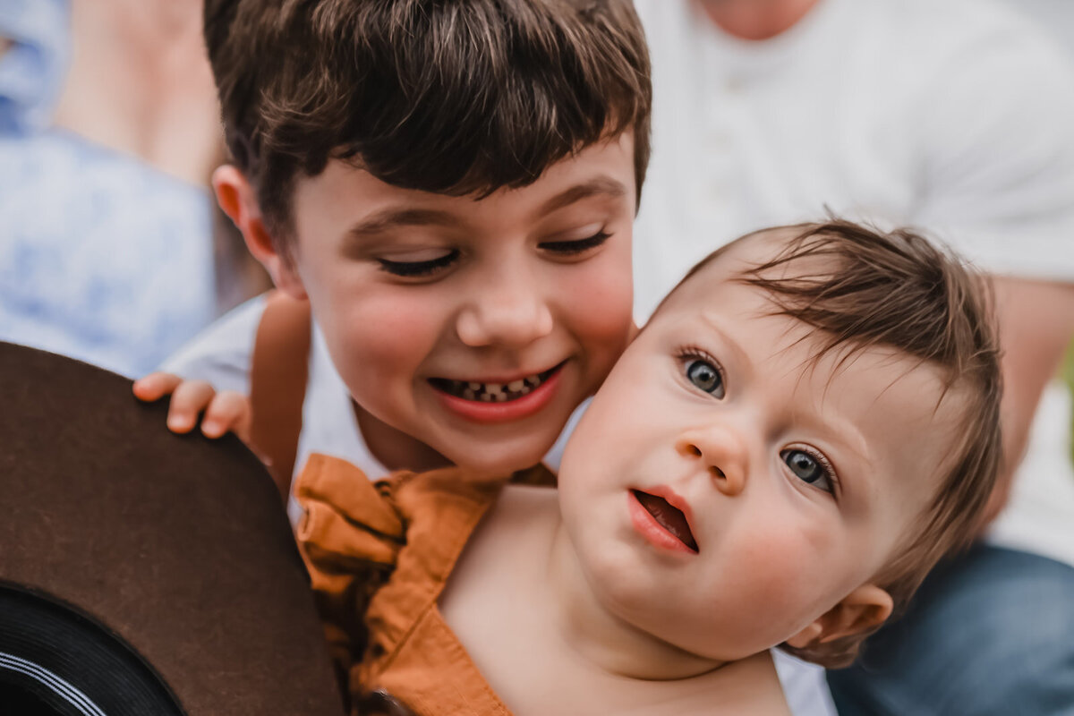 Close-up of brother looking at sister while sister smiles at camera during lifestyle session in New Braunfels, Texas.