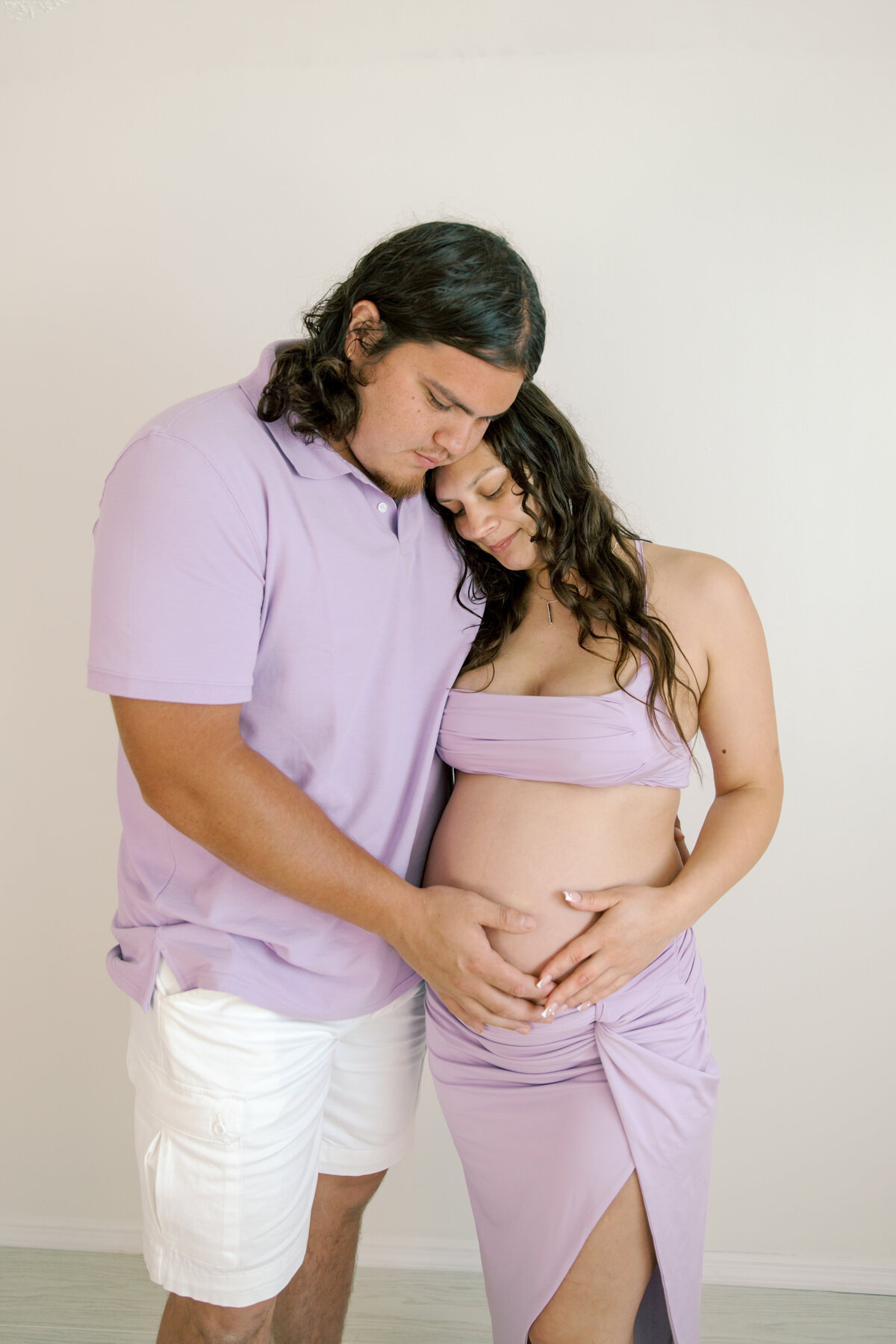 maternity photography spokane with a couple looking down at baby bump in spokane photography studio