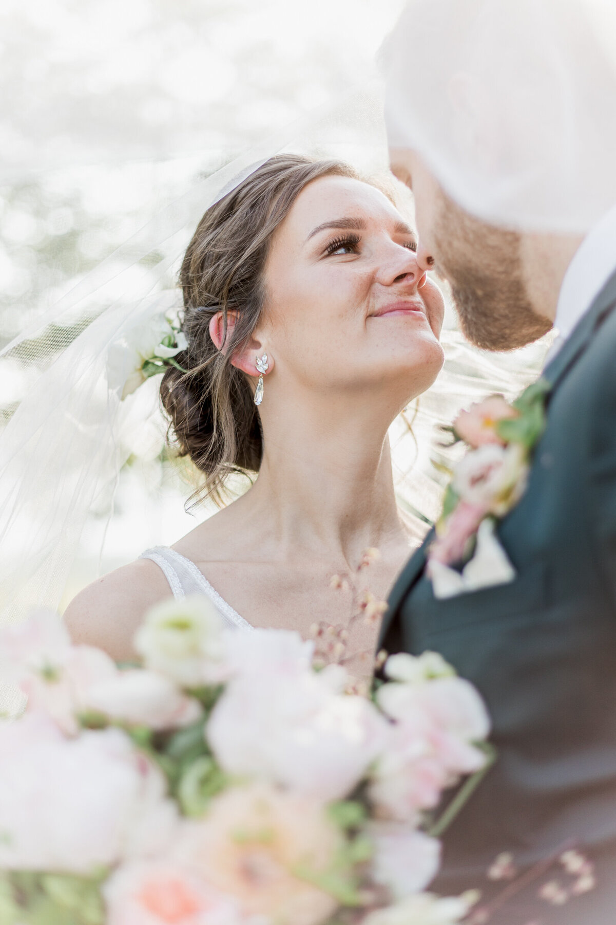 Bride and groom go in for a kiss under the brides veil