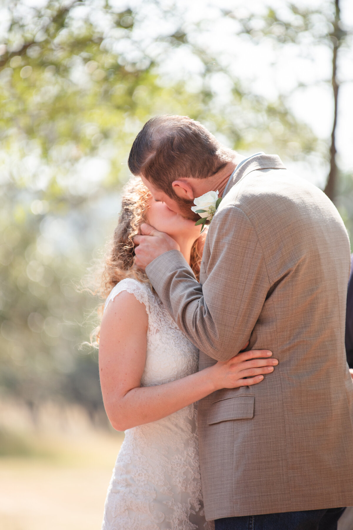 groom in tan jacket kisses bride at Boerne Texas wedding