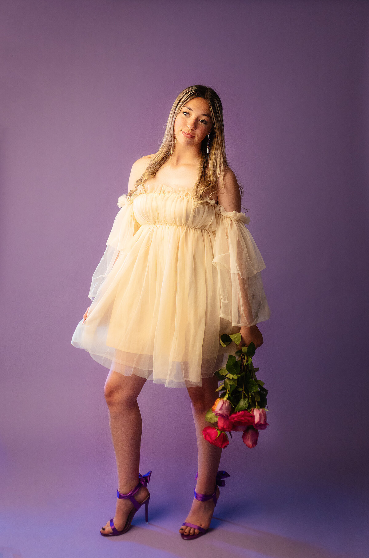 In studio high school senior session with a purple background and fresh flowers