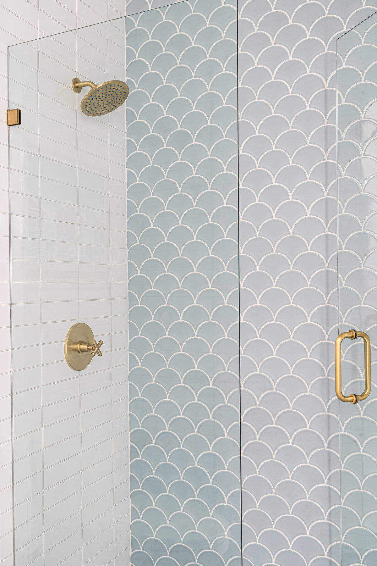 coastal home light blue guest bathroom scalloped shower wall tile and brass fixtures Service Interior Design by Island Home Interiors Lake Nona