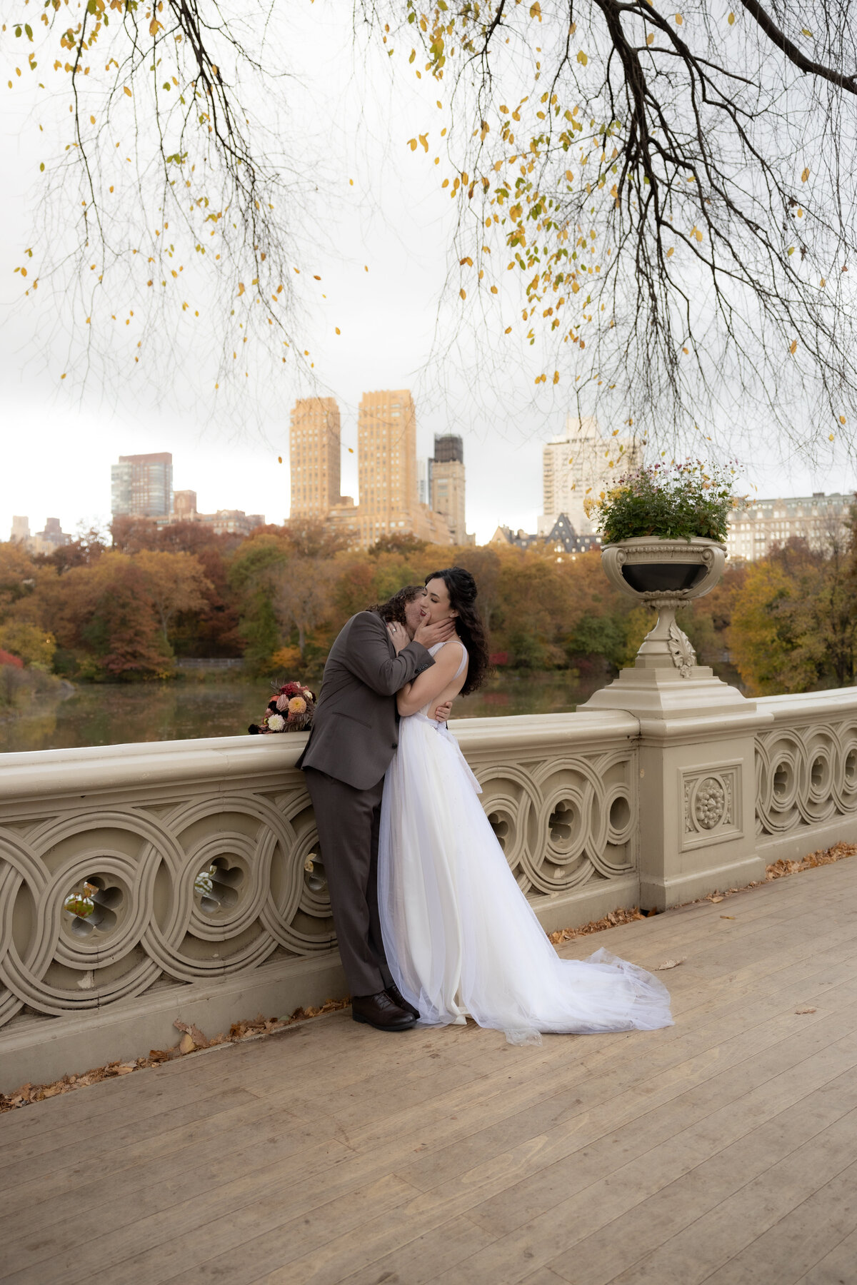 The couple holding hands and smiling as they walk through a peaceful Central Park path.