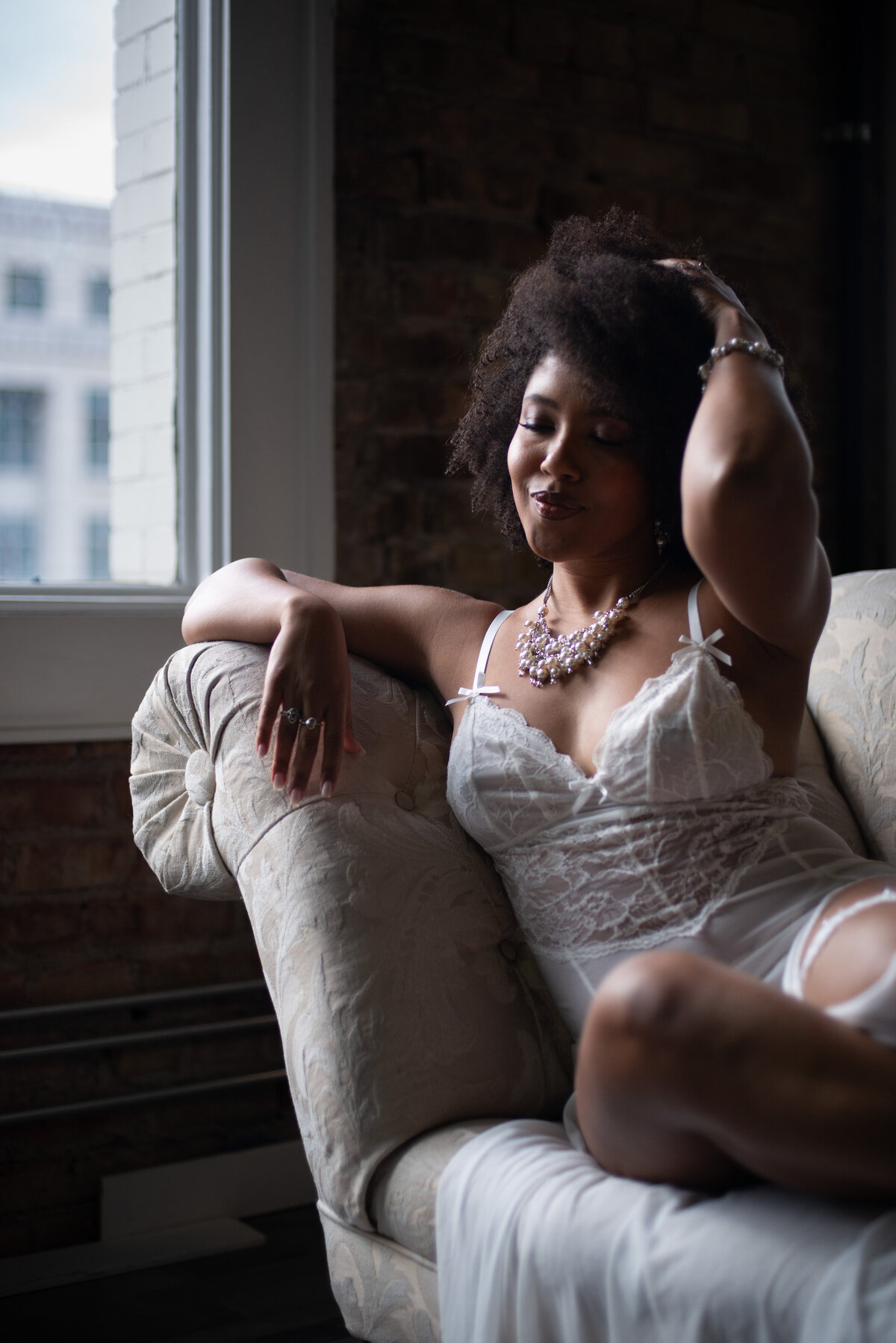 Flirty boudoir pose with a woman playfully  sitting on a sofa
