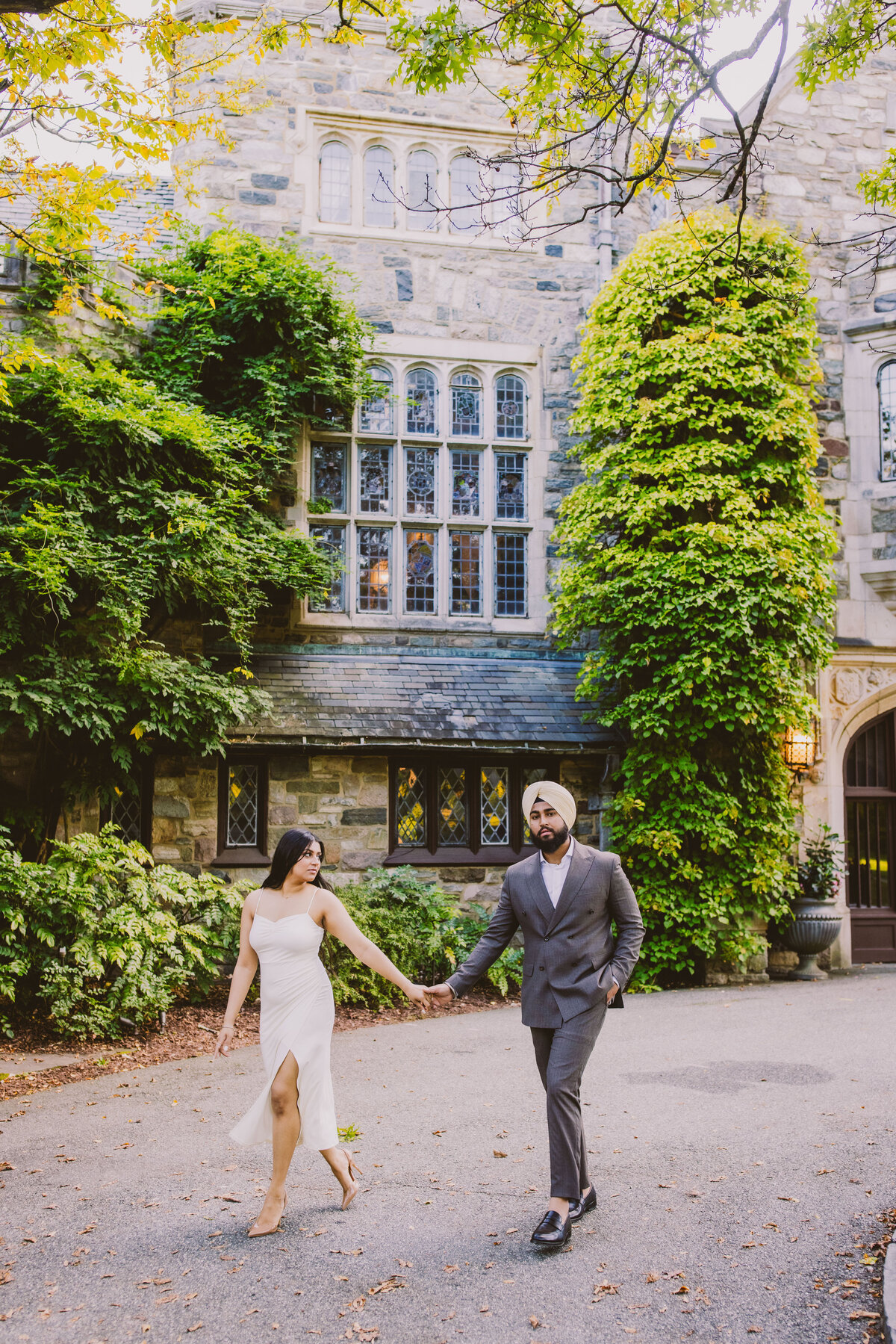 engagement couple walking together in front of the skylands manor mansion at ringwood state park in nj