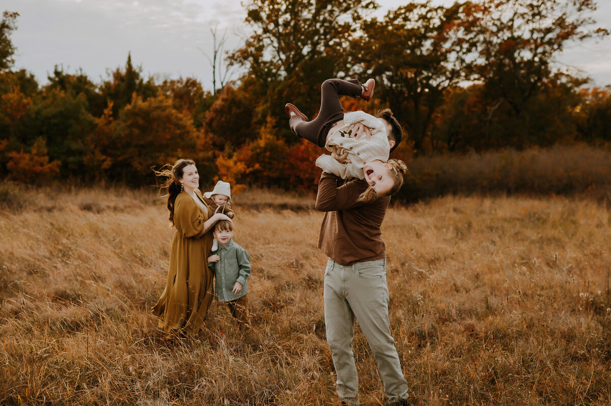The essence of family photography with this image of an Albuquerque family photographer sitting on a white blanket with her beautiful babies. Dressed in a yellow long dress, she is surrounded by lush green grass, highlighting the serene and joyful moments of family life in Albuquerque.