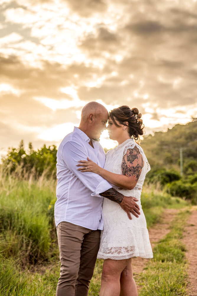 man and woman embracing on the hill at sunset - Townsville Engagement Photography by Jamie Simmons