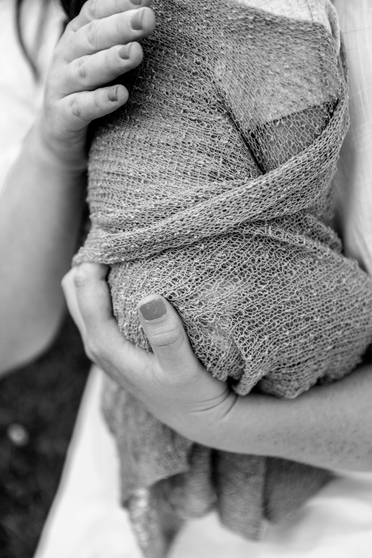 black and white detail shot of newborn photo of mother holding baby in a swaddle