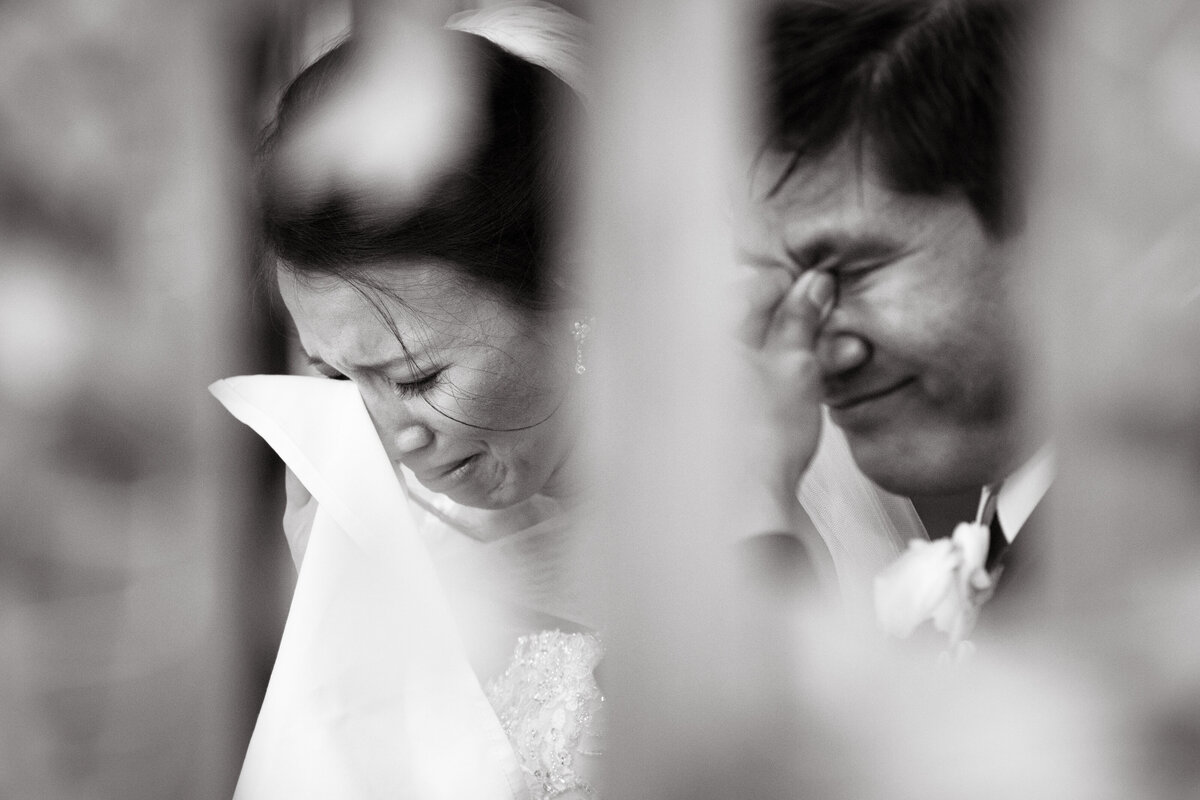 A candid emotional moment of both bride and groom crying.