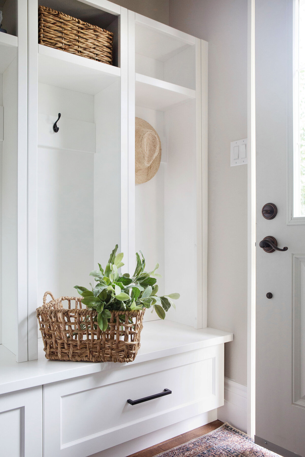 white mudroom built ins styled with wicker basket and vintage print rug
