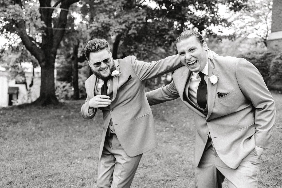 Groom and groomsman laughing and goofing around outside of Common House Charlottesville wedding