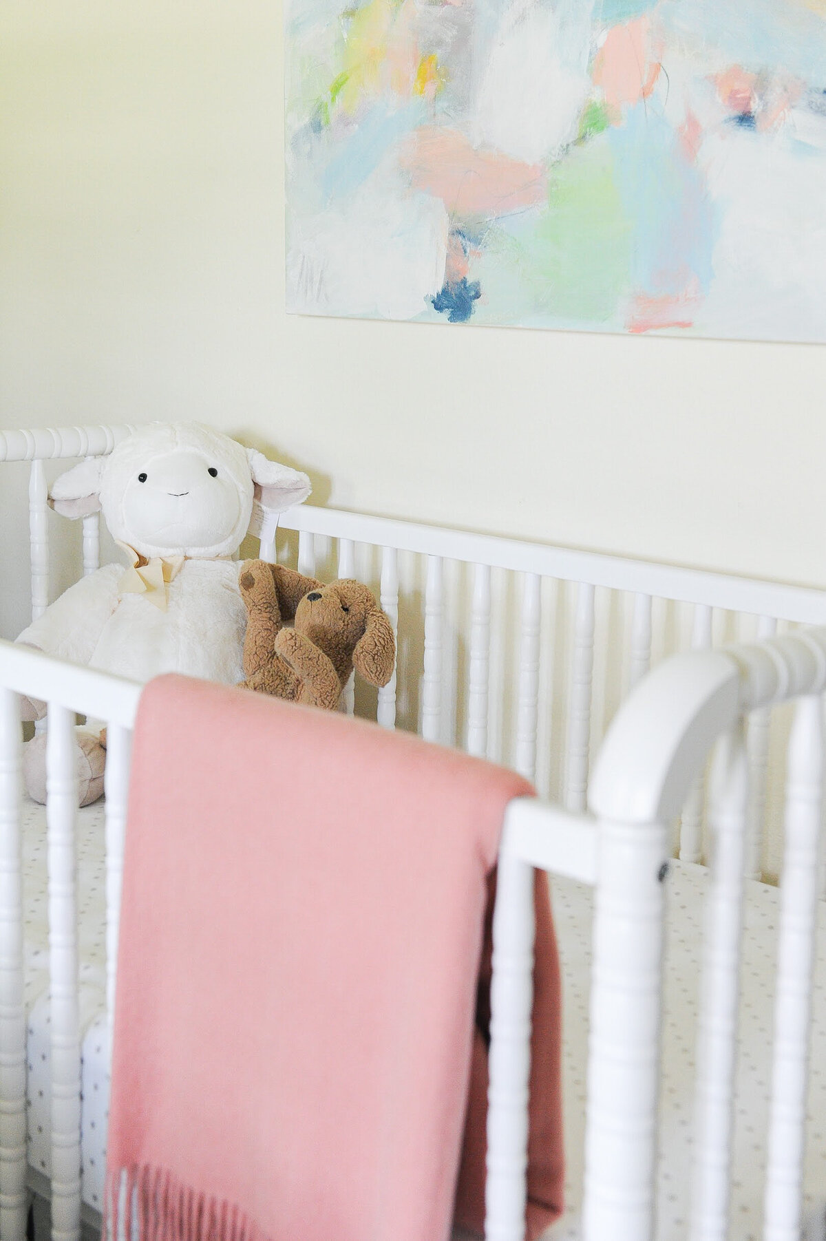 Nursery design of crib with blanket, stuffed animals, and artwork