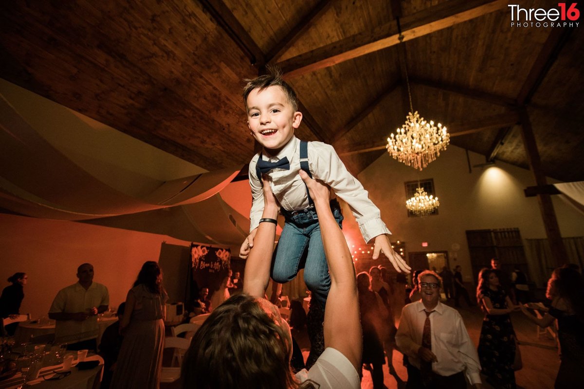 Little boy lifted up in the air at a reception