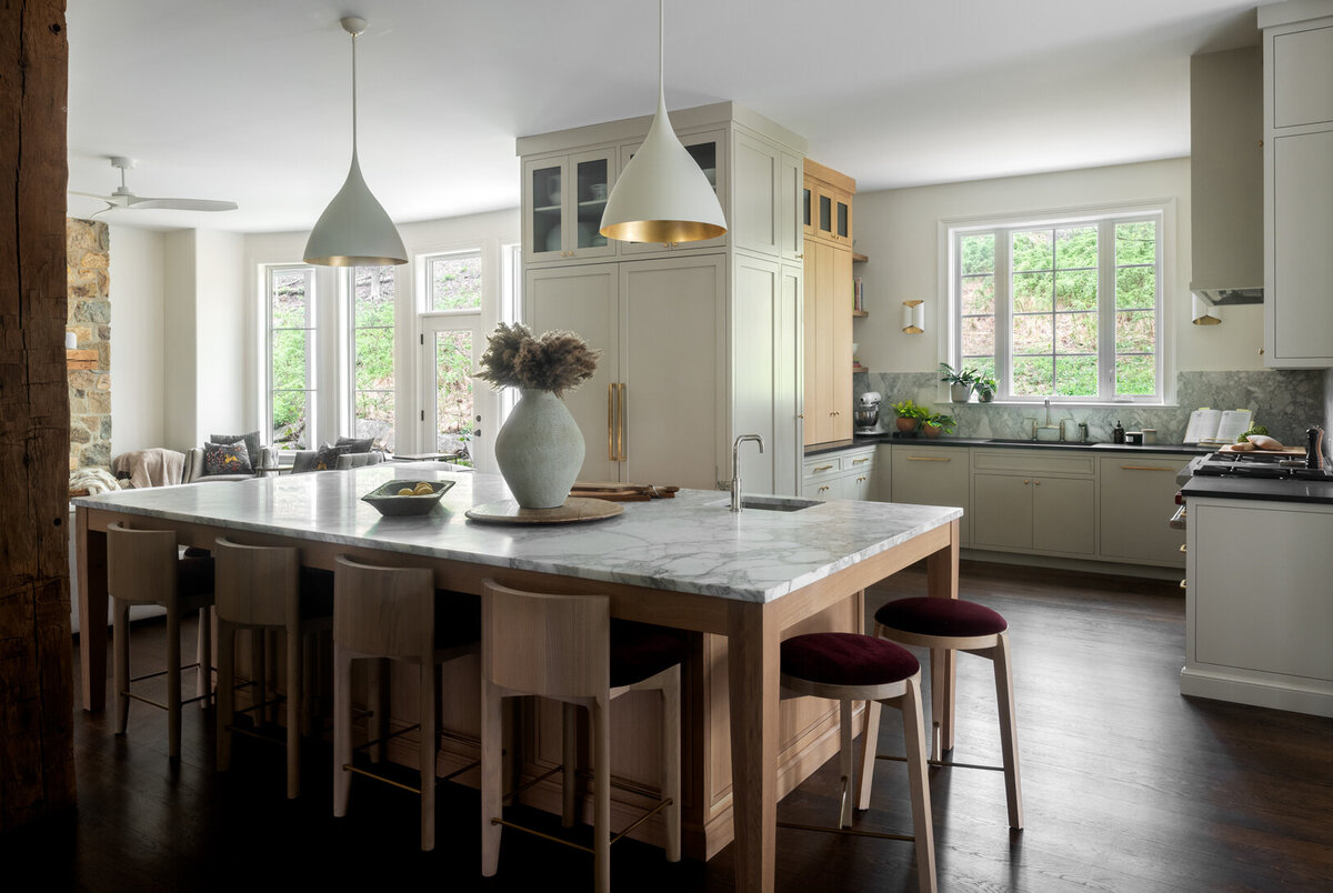 neutral colored kitchen with light wood and gold accents and large marble island top in the middle