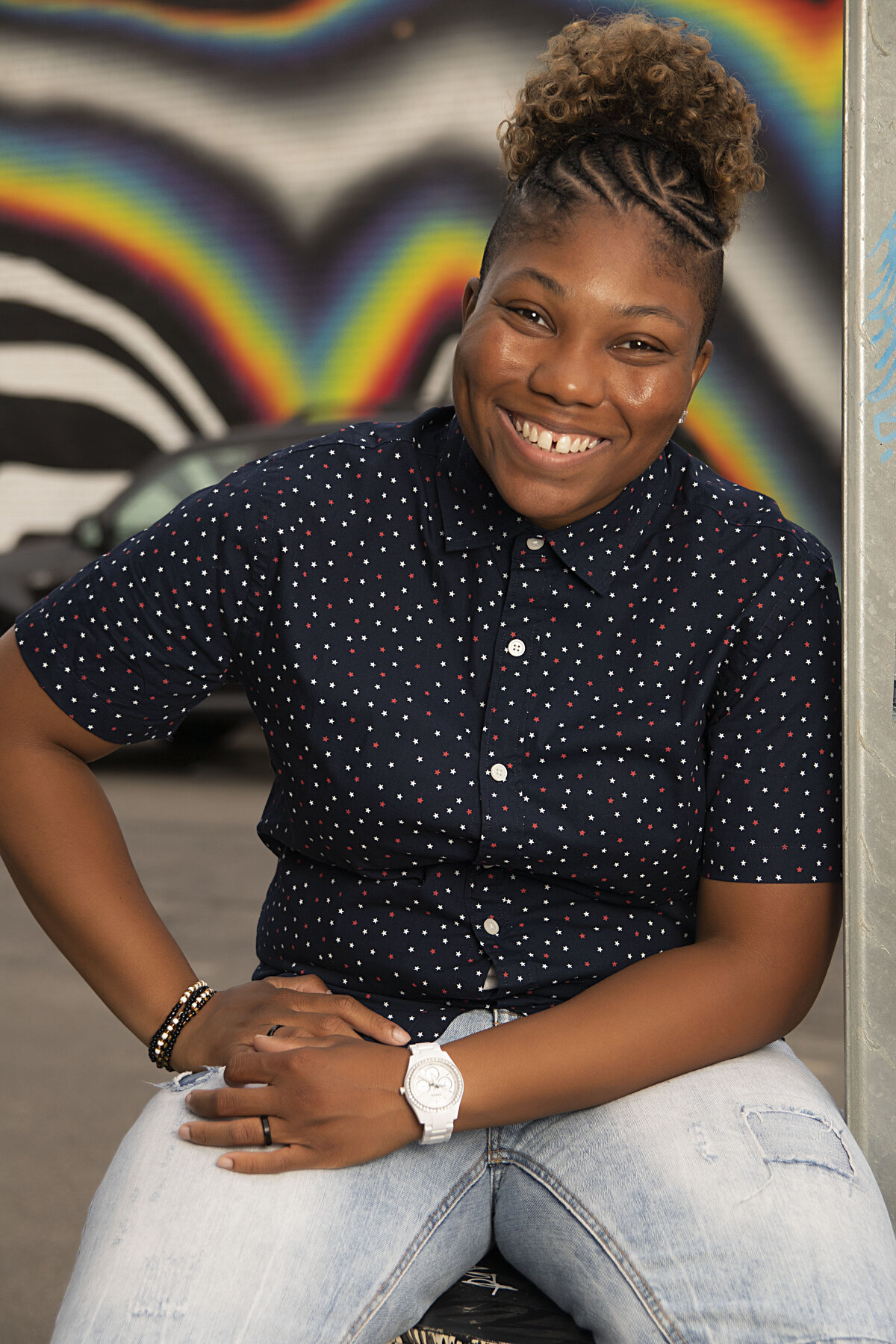 African American woman in blue button up top and blue jean shorts posing casually