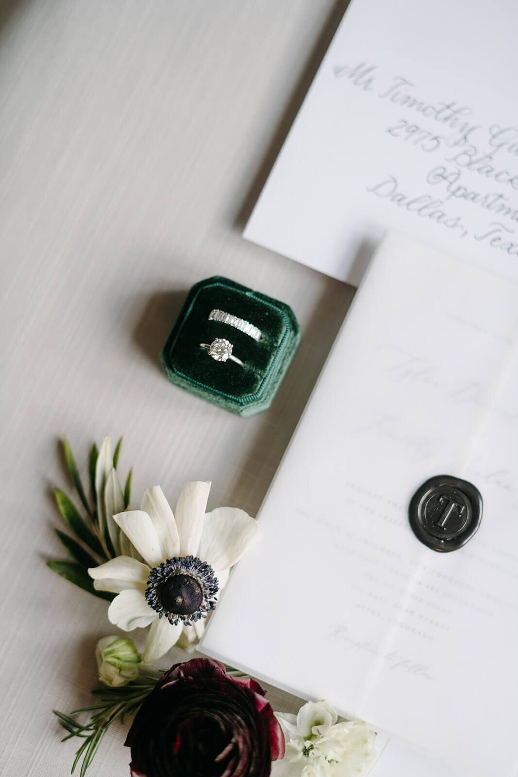 Close-up of wedding invitation and rings at St. Regis Aspen, featuring refined typography, floral details, and neutral tones.