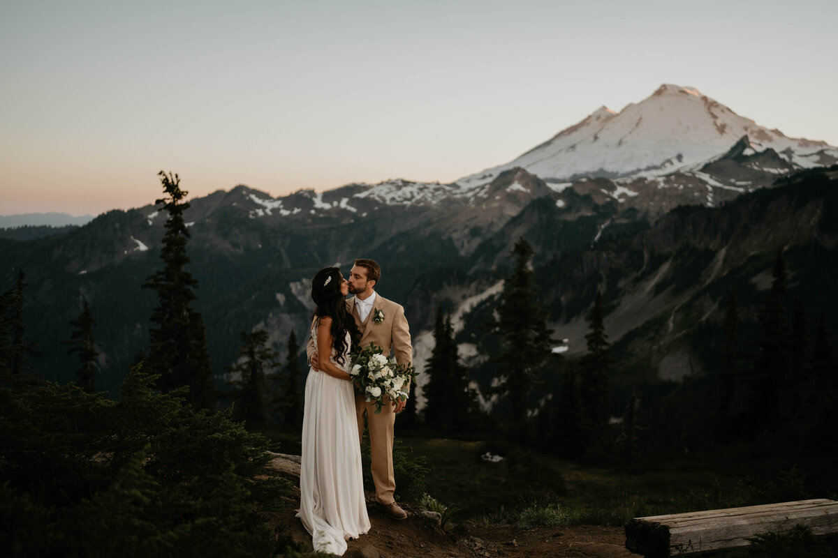 Bride and groom kissing with views of the mountains at North Cascades